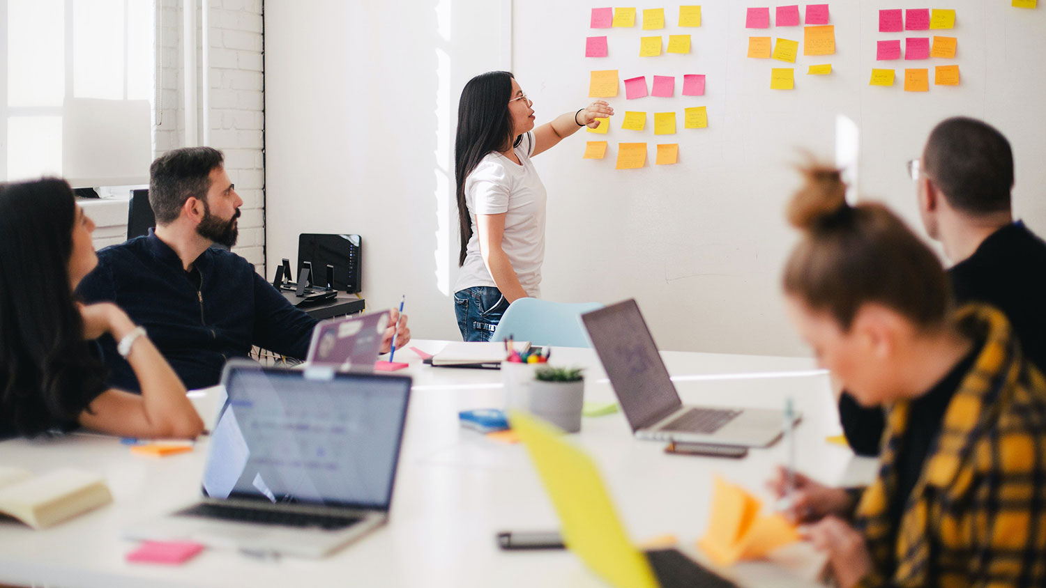 Cornell Engineering student points to sticky notes on wall in front of group of people